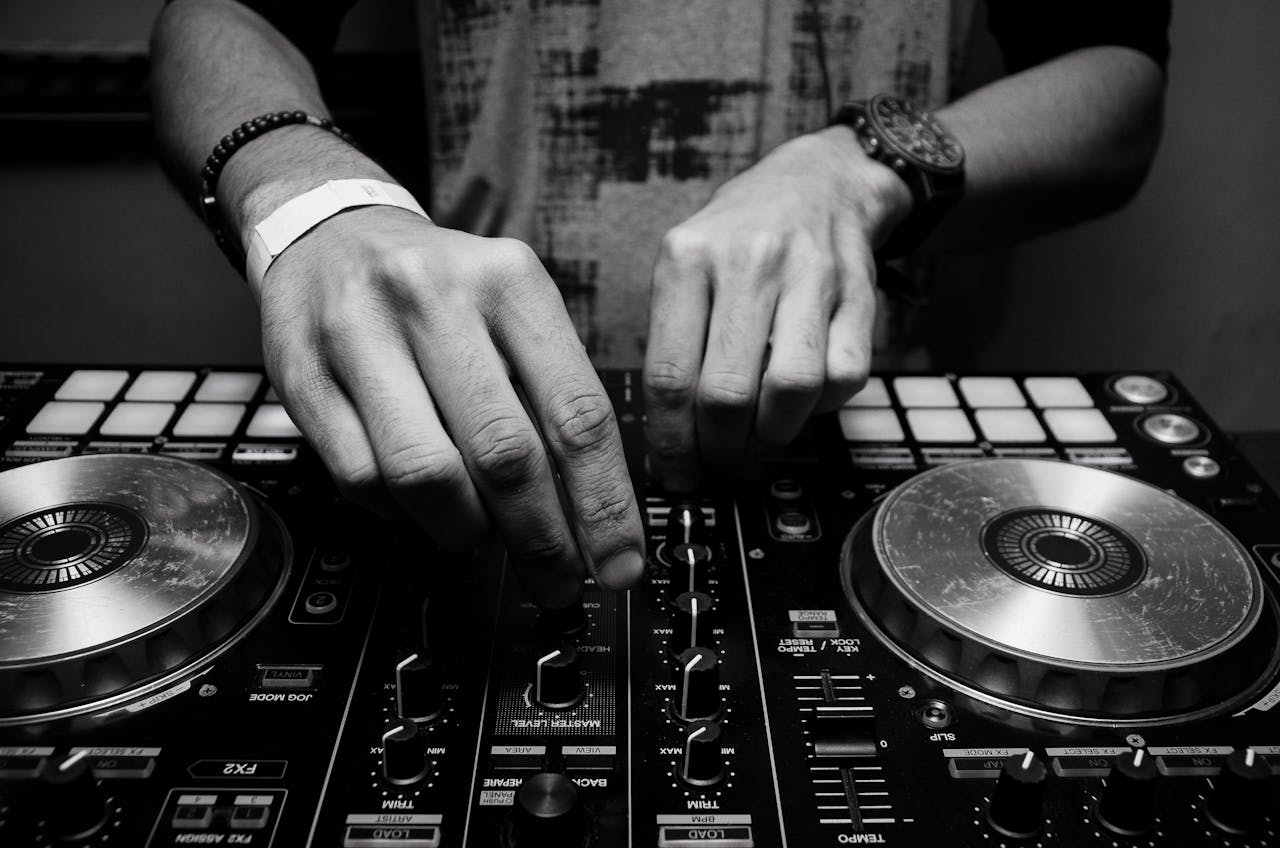 services-04 Close-up of a DJ's hands adjusting controls on a mixer in monochrome.
